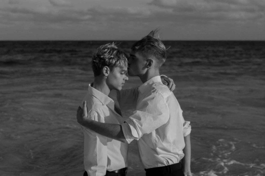 Zwei Männer umarmen sich am Meer, schwarz-weiß